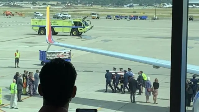 Các nhân viên sân bay đứng nghiêm khi linh cữu cựu binh Col Knight được đưa ra khỏi máy bay