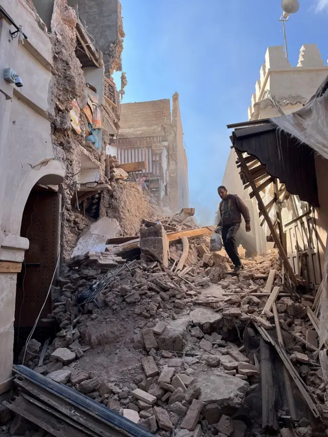 Un hombre camina entre los escombros