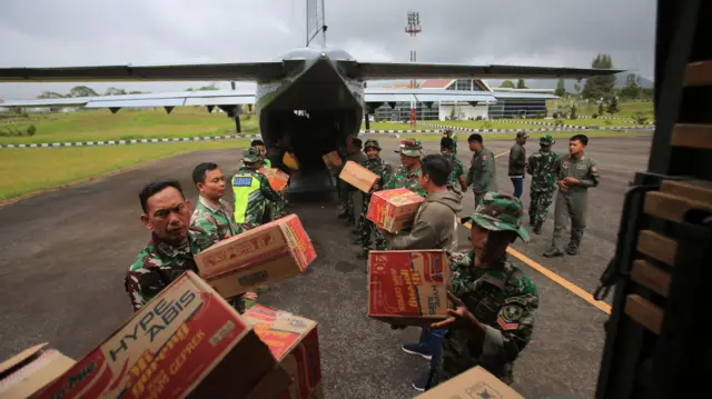 Petugas menurunkan logistik bencana dari pesawat Cassa U-6211 saat tiba di daerah wilayah terisolir Bandara Rembele, Kabupaten Bener Meriah, Aceh, Selasa (2/12/2025).