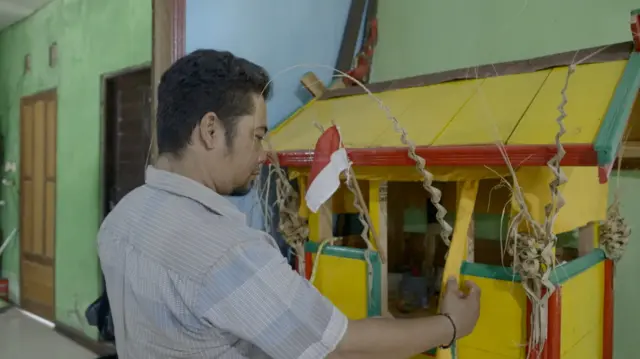 Sajie sedang membersihkan rumah Patahu miliknya. Meskipun sudah menganut agama Kristen, tapi beberapa kepercayaan Kaharingan masih dipegangnya.