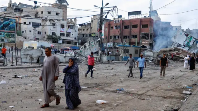 Palestinos caminham ao ladoroleta aovivoedifícios destruídos após os ataques israelenses,roleta aovivoKhan Younis, no sul da Faixaroleta aovivoGaza