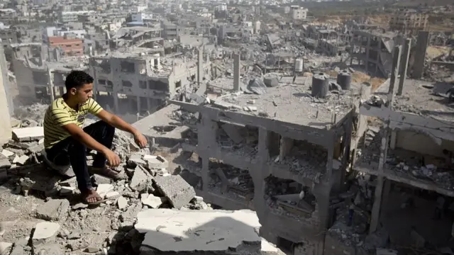 طفل يجلس فوق منزل مدمر