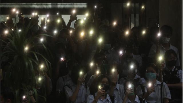 學生們打開手機閃光燈表示抗議。