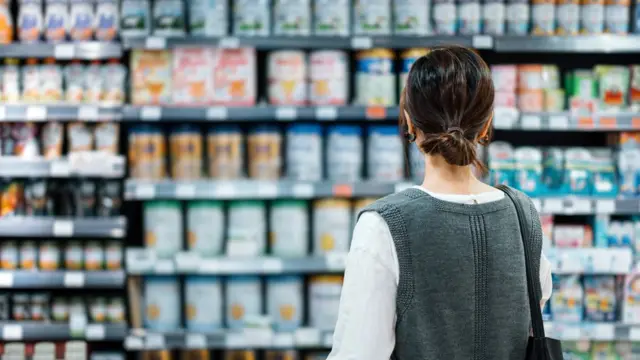 ਸੂਪਰ ਮਾਰਕਿਟ ਵਿੱਚ ਉਤਪਾਦ ਦੇਖ ਰਹੀ ਔਰਤ