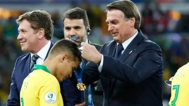 Brezilya Devlet Başkanı Jair Bolsonaro, 2019'da Copa America'yı kazanan milli takım oyuncularına madalyalarını takıyor
