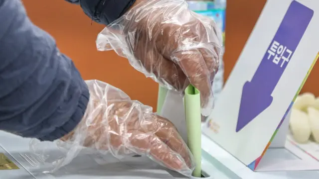 비닐장갑을 착용한 유권자가 투표를 하고 있다