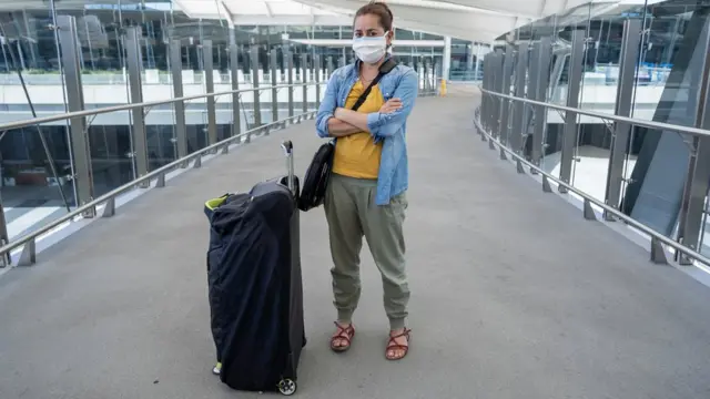 Mulhervaidebet gemáscara, braços cruzados e ao ladovaidebet gemalavaidebet gecorredorvaidebet geaeroporto