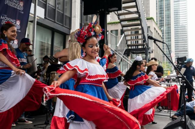 El ambiente durante el desfile dominicano mientras los bailarines se presentan en el escenario de la Sexta Avenida de Nueva York, Estados Unidos, el 8 de agosto de 2021.
