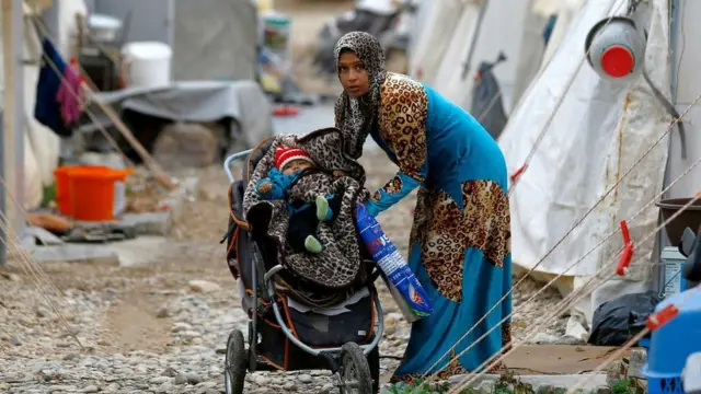 A Syrian refugee mother puts her baby into a stroller in Nizip refugee camp, near the Turkish-Syrian border in Gaziantep province, Turkey, 30 November, 2016.