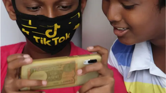 দুই বালক মোবাইল ফোন দেখছে।