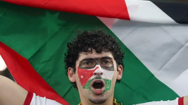  قام مشجع أردني بتلوين وجهه بألوان علم بلاده بينما كان يرفع العلم فوق رأسه قبل مباراة المجموعة العاشرة من كأس العالم 2026 بين الأردن والأرجنتين، والتي أقيمت في 27 يونيو/حزيران 2026 على ملعب دالاس في دالاس، تكساس.