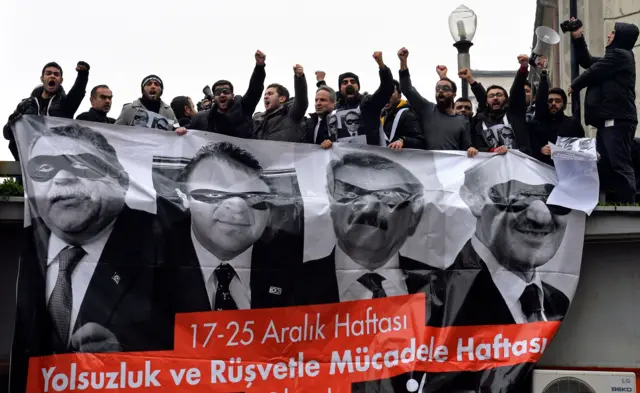 17 Aralık 2014 tarihinde Ankara'da düzenlenen bir protesto gösterisi sırasında, CHP destekçileri, dört eski bakanın fotoğraflarının yer aldığı bir pankart tutarken hükümet karşıtı sloganlar atıyor. Pankartta eski İçişleri Bakanı Muammer Güler, eski Avrupa İşleri Bakanı Egemen Bağış, eski Ekonomi Bakanı Zafer Çağlayan ve eski Çevre ve Şehir Planlama Bakanı Erdoğan Bayraktar'ın fotoğrafları var.