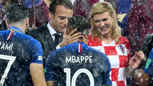 Le président de la France, Emmanuel Macron, et la présidente de la Croatie, Kolinda GrabarKitarovic, embrassent Kylian Mbappe, lors de la cérémonie de remise des trophées