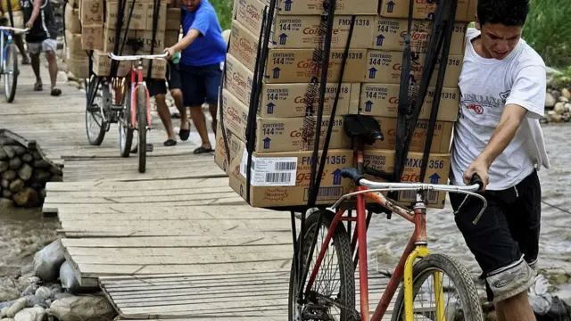 PEssoas carregando caixasbicicletas