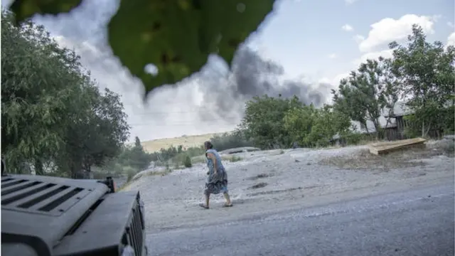 صورة أرشيفية لامرأة تهرب من القصف على إحدى مناطق دونيتسك