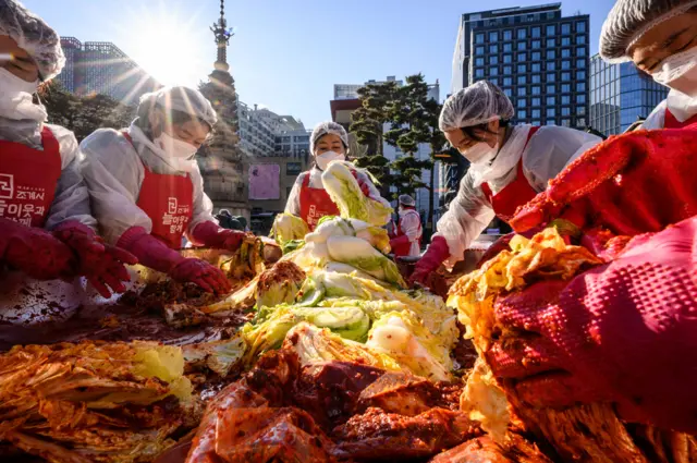Participants prepare kimchi, a traditional Korean dish of spicy fermented cabbage and radish, during a kimchi making festival at the Jogyesa Buddhist temple in Seoul on 2 December 2021, before it is distributed among the less privileged from the local neighbourhood