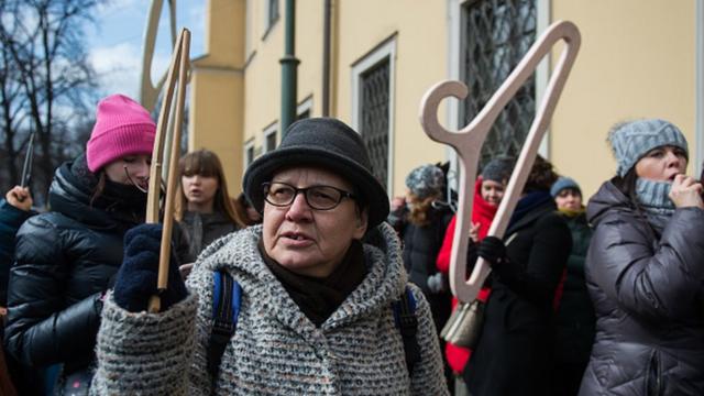 Mujer sostiene una percha en manifestación sobre el aborto.