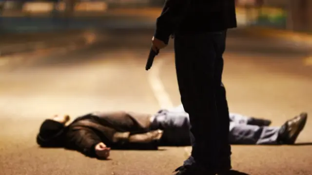 Sicario y un hombre tendido en el suelo