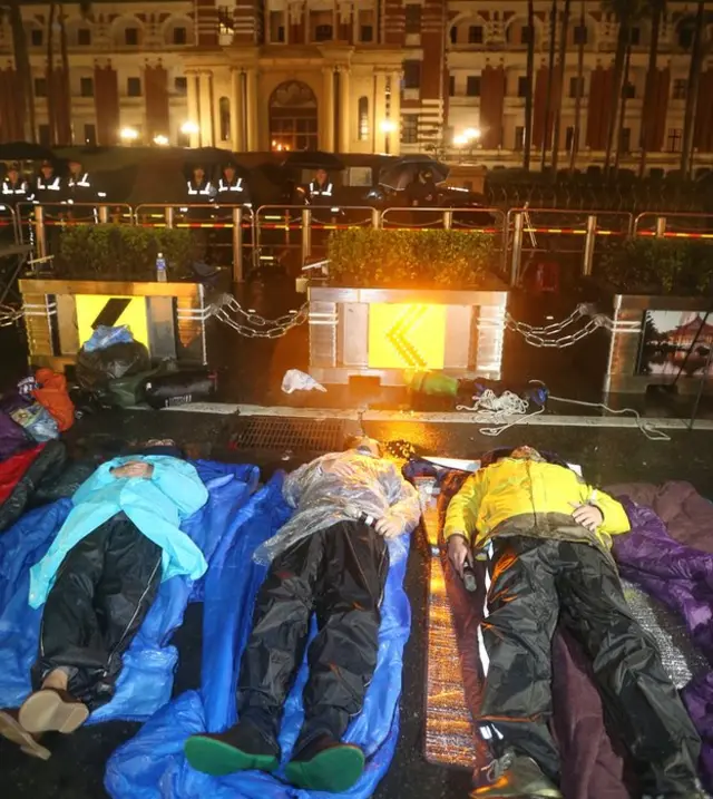 警方在7日凌晨强拆帐篷,预备下一波驱离动作,黄国昌(右)与徐永明(中)等人继续躺在雨中。