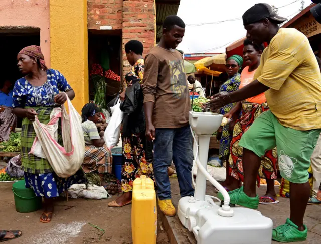 A man washes his hands at a public hand washing station before boarding a bus as a cautionary measure against the coronavirus at Nyabugogo Bus Park in Kigali in Rwanda.