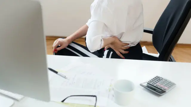 Mujer en silla con dolor de espalda