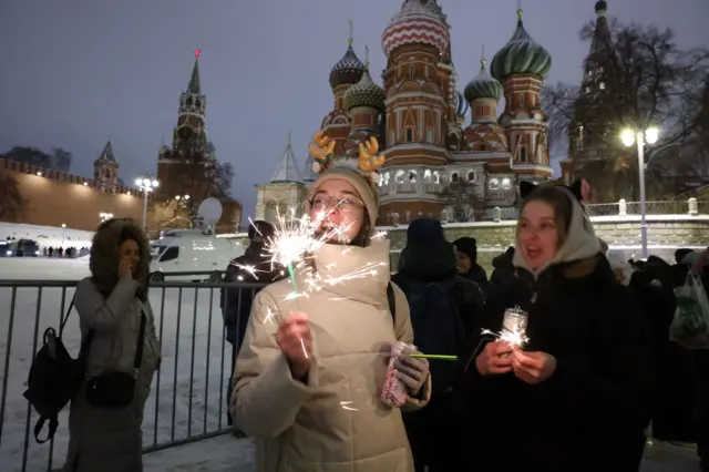 فتاة تشعل ألعابا نارية بجوار الساحة الحمراء في موسكو المغلقة أمام الزوار خلال احتفالات رأس السنة الجديدة