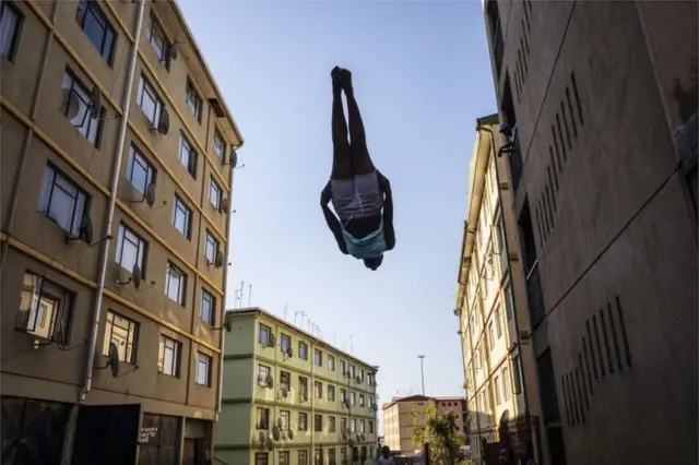 A young woman appears to hover mid-air as the jumps on a trampoline, which is hidden out of the shot.