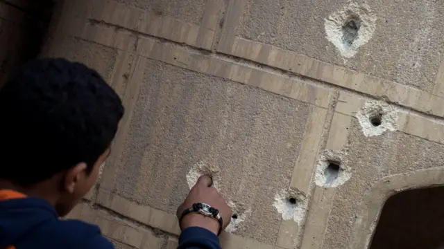 A man fingers bullet holes in a wall outside Mar Mina church following an attack on the church in the district of Helwan, south-eastern Cairo, Egypt, 29 December 2017