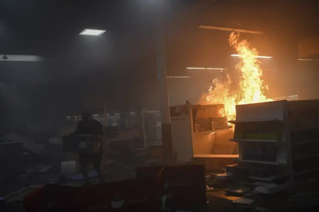 15. A man loots merchandise and a store burns during unrest resulting from the killing of an unarmed black man, George Floyd, by police.