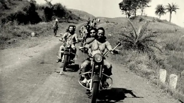 Sheela e seguidores de Osho andando de motocicleta na Índia