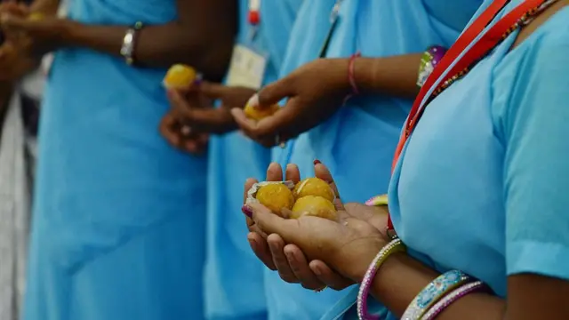 હાથમાં લાડુ લઈને ઊભેલી મહિલાઓ