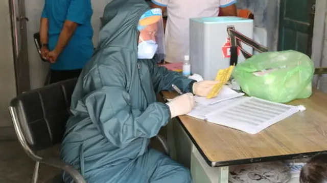 Tenaga medis mengenakan alat perlindungan diri ketika memberikan vaksin kepada anak-anak di Nepal