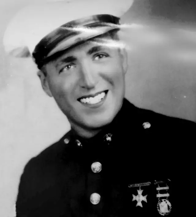 Charles 'Chuck' Morse usando uniforme militar sorri e olha para a câmera