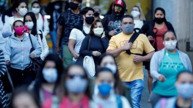 Pessoas andando com máscaras na rua