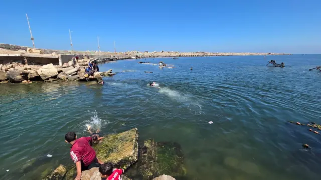 أشخاص بينهم أطفال في البحر مقابل ميناء غزة