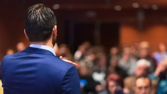 Una persona de espaldas, dando una charla a una audiencia