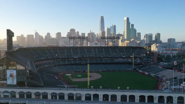 Vista aérea do Oracle Park, onde joga o San Francisco Giants, em dia ensolarado e com prédios ao fundo