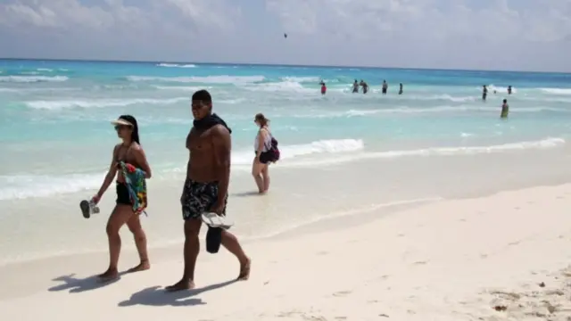Casal caminhando na beira do mar em Cancún
