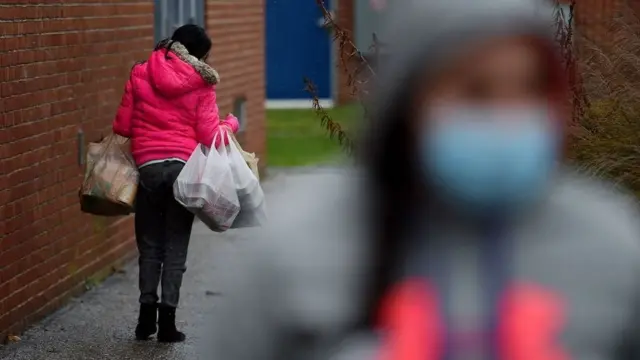 People carry food donated by volunteers from the Baltimore Hunger Project outside of Padonia International Elementary school