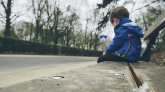 Niño sentado en un banco.