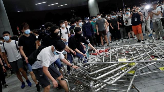 戴着口罩的示威者组拉倒香港立法会大楼门前的铁马（10/6/2019）