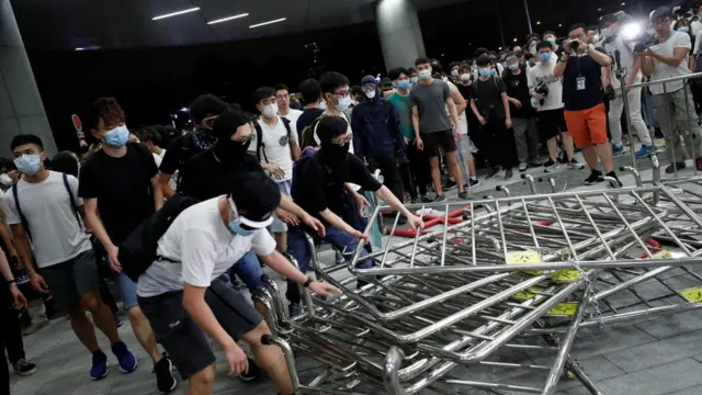 戴着口罩的示威者组拉倒香港立法会大楼门前的铁马(10/6/2019)