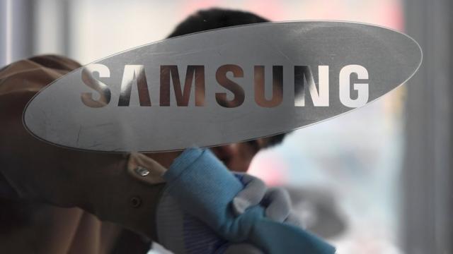 Un hombre limpiando un vidrio con el logo de Samsung.
