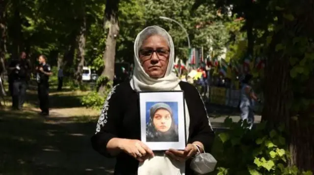 شعله پاکروان مادر ریحانه جباری با عکس دخترش در مقابل سفارت ایران در برلین؛ دختر خانم پاکروان، ریحانه جباری در پرونده‌ای پر ابهام محکوم به قصاص و اعدام شد.