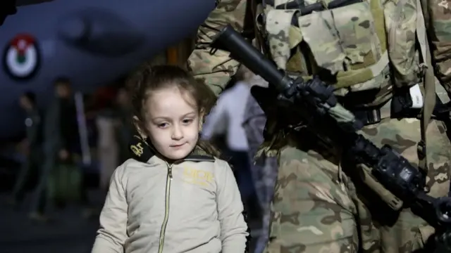 جندي أردني يرافق طفلة في مطار ماركا العسكري في الأردن