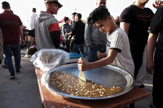 A boy cuts a piece of sweet at a popular market during the holy month of Ramadan in Benghazi, Libya. April 8, 2022. Picture taken April 8, 2022