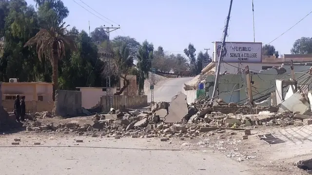 Security personnel (L) stand beside a destroyed security post following overnight attacks by militants on security camps in Naushki district of Balochistan province on February 3, 2022. (Photo by AFP) (Photo by -/AFP via Getty Images)
