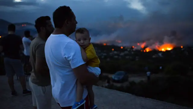 Un grupo de personas observa el incendio forestal cerca de Atenas el 23 de julio de 2018.