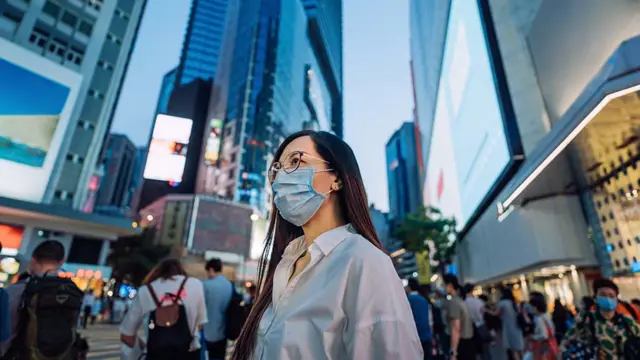 香港铜锣湾闹市一位戴着口罩的女士走过
