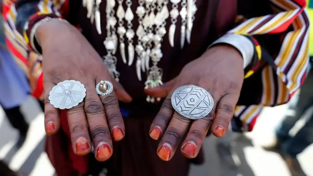 துனிஷியாவின் டேஸியுரில் நடைபெற்ற கலாசார நிகழ்வான ஒயாஸிஸ் பண்டிகையின் கடைசி நாளான வெள்ளிக்கிழமையன்று, லிபியாவின் கிராம குழுவை சேர்ந்த ஒருவர் அவருடையே மோதிரத்தை காட்டுகிறார்.